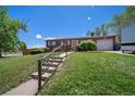 A home with a brick facade and a well-manicured lawn accessible by a stairway, all on a sunny day at 12024 W Maryland Dr, Lakewood, CO 80228