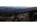 Scenic view of a cozy mountain home nestled among the trees at dusk at 18645 Rocky Top Trl, Littleton, CO 80127