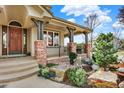Inviting covered porch with stone features, well-maintained garden, and natural color palette at 9164 E Lost Hill Trl, Lone Tree, CO 80124