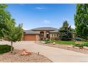 Beautiful home featuring lush landscaping, a stone entryway, and a circular driveway at 3806 S Dawson St, Aurora, CO 80014