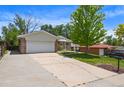 Brick home with front lawn, driveway, and large shade tree offers great curb appeal at 6432 Zephyr St, Arvada, CO 80004