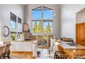 Bright living room with tall windows offering scenic views, stone fireplace, and seamless access to the kitchen at 180 Emmett Lode Rd, Breckenridge, CO 80424