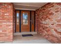 Close-up of the decorative wooden front door with glass sidelights and a brick facade, creating a welcoming entrance at 7310 S Sheridan Ct, Littleton, CO 80128