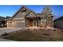 Inviting home with a manicured lawn, stone accents, a two-car garage and covered porch with chairs at 2882 Heron Lakes Pkwy, Berthoud, CO 80513
