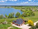 Aerial front exterior of brick home boasts mature trees and landscaping and a lake view in the background at 2366 Shoreside Dr, Berthoud, CO 80513