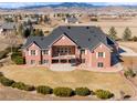 Aerial view of a large brick home showcasing an upper balcony and a lower patio at 2366 Shoreside Dr, Berthoud, CO 80513