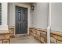 Close-up of a stylish front door with stone accents and modern lighting at 5395 Canyon View Dr, Castle Rock, CO 80104