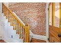 Elegant staircase featuring exposed brick wall and classic wood banister and door at 2543 Stout St, Denver, CO 80205