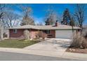 Charming brick home showcasing a well-kept lawn and a spacious driveway leading to the garage at 6930 S Delaware St, Littleton, CO 80120