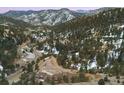 Aerial view of the hillside community surrounded by wooded areas and snow-capped mountains at 21609 Clarence Ln, Golden, CO 80401