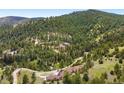 Remote wooded acreage with a sprawling home featuring a long driveway and beautifully landscaped grounds at 21609 Clarence Ln, Golden, CO 80401
