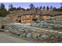 Backyard of the house showcasing a stone patio, string lights, and natural rock landscaping at 21609 Clarence Ln, Golden, CO 80401