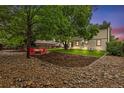 Expansive backyard featuring mature trees, red adirondack chairs, and a gravel-lined firepit, perfect for outdoor relaxation at 1285 Aberdeen Dr, Broomfield, CO 80020
