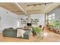 Bright living room featuring wood floors, exposed ductwork, and an abundance of thriving houseplants at 290 W 12Th Ave # 205, Denver, CO 80204