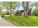 Attractive front yard with lush green lawn, mature trees, and brick facade in a desirable neighborhood at 7503 Saulsbury St, Arvada, CO 80003