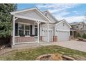Close-up of a well-manicured gray home featuring a welcoming front porch and attached two-car garage at 1757 Baguette Dr, Castle Rock, CO 80108