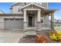 Inviting front porch with stone accents, neutral colors, and well-maintained landscaping at 9479 Rifle St, Commerce City, CO 80022