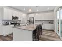 Bright kitchen featuring white cabinets, stainless steel appliances, and a large center island with bar seating at 9479 Rifle St, Commerce City, CO 80022