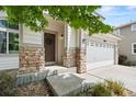 Inviting entryway with stone pillars, a decorative wreath on the brown front door, and a spacious two-car garage at 10681 Cherrybrook Cir, Highlands Ranch, CO 80126