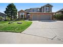 Charming two-story brick and siding home with a manicured lawn, mature trees, and a spacious driveway at 10520 W Vassar Dr, Lakewood, CO 80227