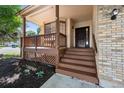 Inviting covered porch featuring classic wood railing, brick accents, and a welcoming entry at 3838 S Waco St, Aurora, CO 80013