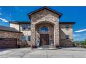 Grand home entrance with stone archway, double doors, and manicured landscaping at 7343 Upton Ct, Castle Rock, CO 80104