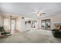 Spacious carpeted living room with ceiling fan, adjacent kitchen and fireplace at 15623 Degaulle Cir, Brighton, CO 80603
