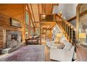 Comfortable living room boasts a stone fireplace and exposed wood beam vaulted ceilings at 80 Spruce Ct, Evergreen, CO 80439
