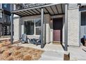 Covered front porch with brick facade and two adirondack chairs at 12387 W 51St Ave, Wheat Ridge, CO 80033