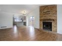 Open living room with wood floors, brick fireplace and open concept access to the kitchen at 4542 S Quintero St, Aurora, CO 80015