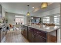 Granite kitchen island with pendant lights, dark cabinetry, and an open view into the dining and living area at 1158 Sugarloaf Ln, Erie, CO 80516