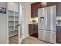 Walk-in pantry with ample shelving located next to stainless steel fridge and dark wood cabinets at 1158 Sugarloaf Ln, Erie, CO 80516