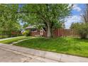 Well-maintained front yard with a classic brick home and mature trees in a quiet neighborhood at 7192 W 67Th Pl, Arvada, CO 80003