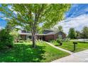 Beautifully landscaped front yard of a brick home with mature tree and paved walkway at 10289 E Berry Dr, Greenwood Village, CO 80111