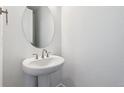 Half bath featuring a pedestal sink and modern round mirror at 9266 Telluride Ct, Commerce City, CO 80022