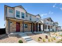 View of a row of townhomes featuring stone facades, covered porches, and well-maintained landscaping at 18712 E 99Th Ave, Commerce City, CO 80022