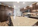 A kitchen with a large center island, stainless steel appliances, and dark brown cabinets at 2225 Santini Trl # C, Littleton, CO 80129