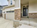 Charming front porch with stone accents, black front door, and three-car garage at 11657 Olathe St, Commerce City, CO 80022