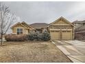 Well-maintained home featuring a two-car garage, stone accents, and landscaped front yard at 424 N De Gaulle Ct, Aurora, CO 80018