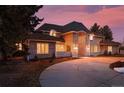 Elegant brick home with a dramatic sunset in the background at 66 Charlou Cir, Cherry Hills Village, CO 80111