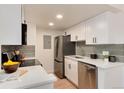 Modern kitchen with white cabinets, stainless steel appliances, and a stylish tile backsplash at 8335 Fairmount Dr # 7-208, Denver, CO 80247