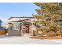 Charming single-story home featuring a red front door, covered porch, and mature evergreen tree at 185 S Eliot St, Denver, CO 80219