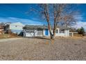 Cozy home with blue door, white brick, black shutters, and gravel landscaping at 7604 Reed St, Arvada, CO 80003