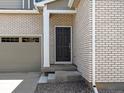 Home entrance featuring a dark door, brick facade, and gray gravel landscaping at 552 Red Rock Pl, Brighton, CO 80601