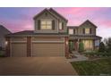 Charming two-story home with a three-car garage, brick accents, and a well-manicured lawn at sunset at 18225 E Caley Dr, Aurora, CO 80016