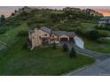 A high angle of a landscaped home with stone accents and an attached three-car garage near a rocky mountain at 6402 Wauconda Dr, Larkspur, CO 80118