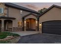 Close up of the facade of the house, with stone detailing, dark garage door, and front entrance at 6402 Wauconda Dr, Larkspur, CO 80118