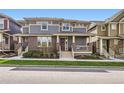 Inviting two-story townhome with brick accents, covered porch, and manicured lawn at 5983 Fulton St, Denver, CO 80238