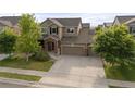 Suburban two-story home features a wide driveway, three-car garage and brick-accented front porch at 41 Jordan Ln, Erie, CO 80516