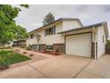 View of a two story home with a well kept lawn and a spacious driveway leading to the garage at 744 Memphis St, Aurora, CO 80011
